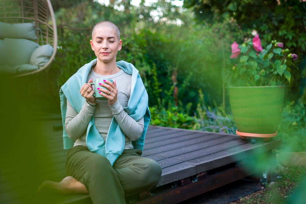 Young,female,cancer,patient,sitting,on,garden,patio,with,coffee,